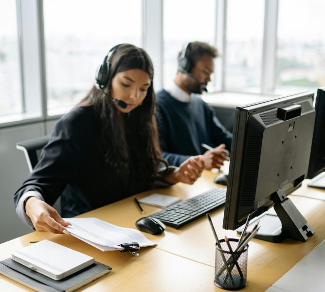 Call center agents handling customer inquiries at modern office desks, focused and professional.